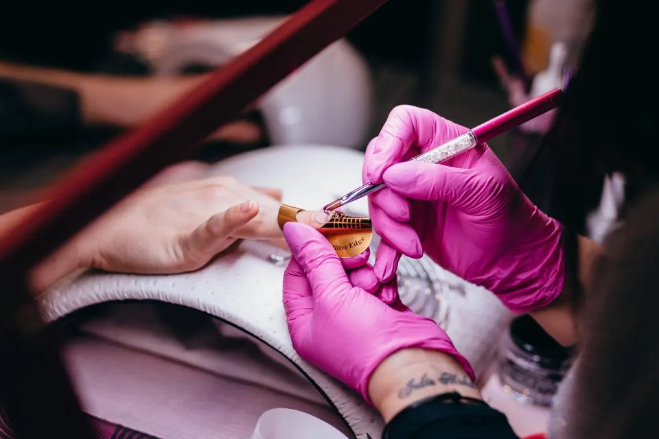 Manicura pintando la uña de una clienta en el salón